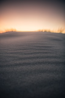 A serene desert landscape with soft sand dunes under a twilight sky.