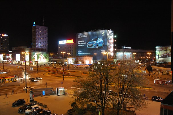 Nighttime cityscape with illuminated billboards featuring the latest automotive technology