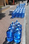 a row of blue water bottles sitting on the side of a road