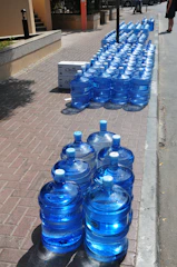 A realtor delivering neatly stacked Airtis water gallons to residential area in natural light.