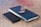 Glasses resting on a wooden desk next to a smartphone and notebook.