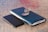 Glasses resting on a wooden desk next to a smartphone and notebook.
