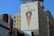 A large outdoor advertisement is painted on the side of a building, depicting a whiskey bottle inside a waffle cone. The ad promotes Crown Royal Vanilla, with the tagline 'Vanilla So Good.' Surrounding the mural are various buildings, including one with a vertical parking sign.