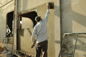 a man standing next to a building with a hammer