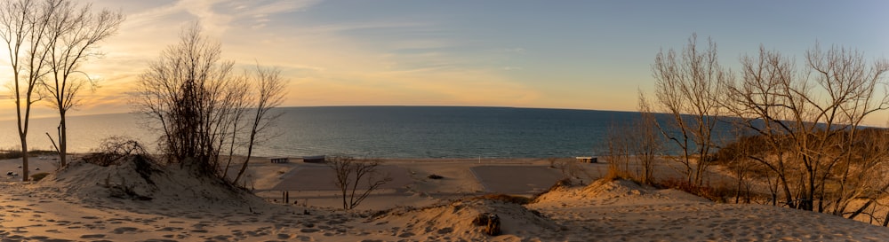 the sun is setting over the water and sand dunes