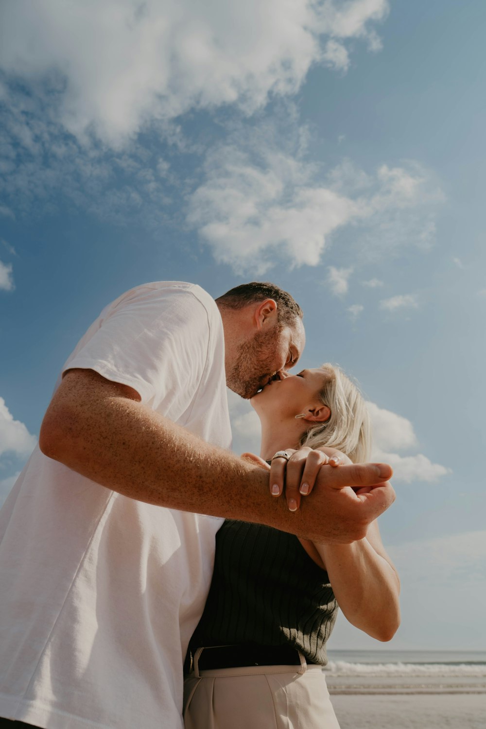 a man and a woman kissing on the beach