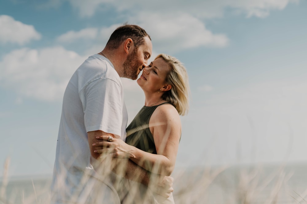 a man and a woman embracing in a field of tall grass