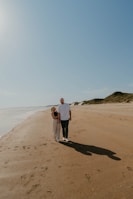 Couple walking along a sandy shore with clear blue water