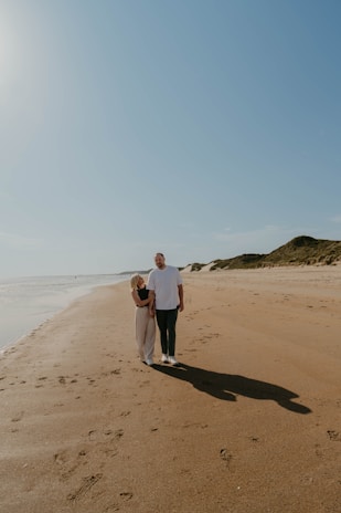 Happy couple enjoying a sunny beach vacation with clear blue skies.