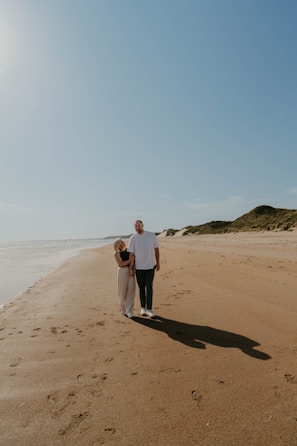 Couple walking along a sandy shore with clear blue water
