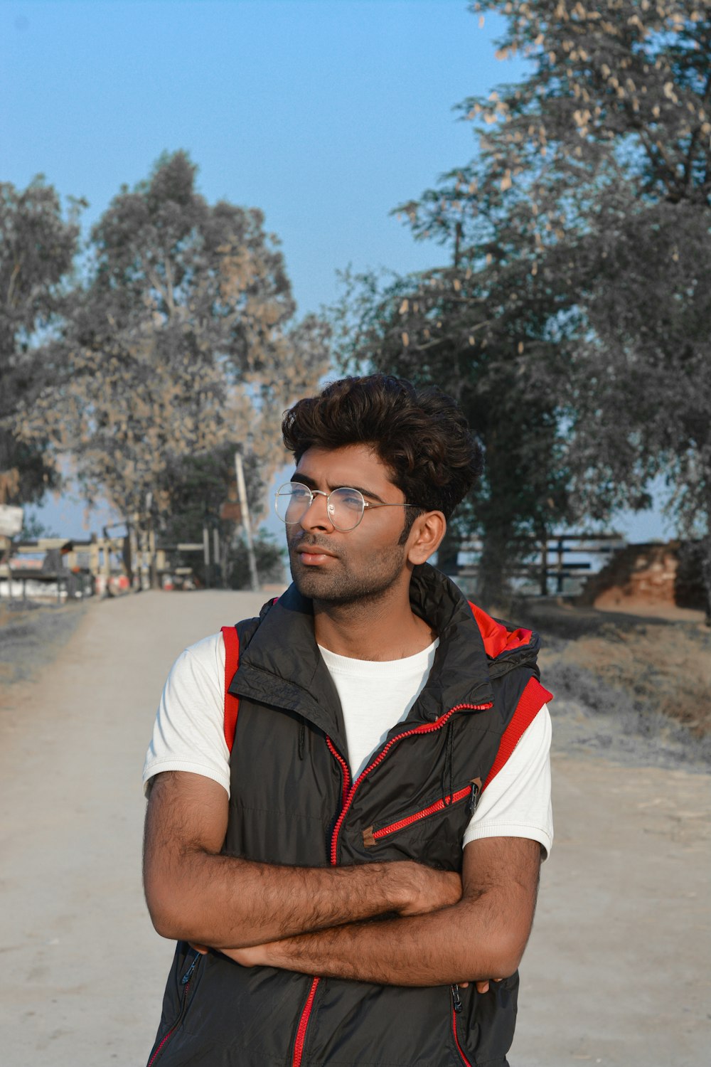 a man standing on a dirt road with his arms crossed