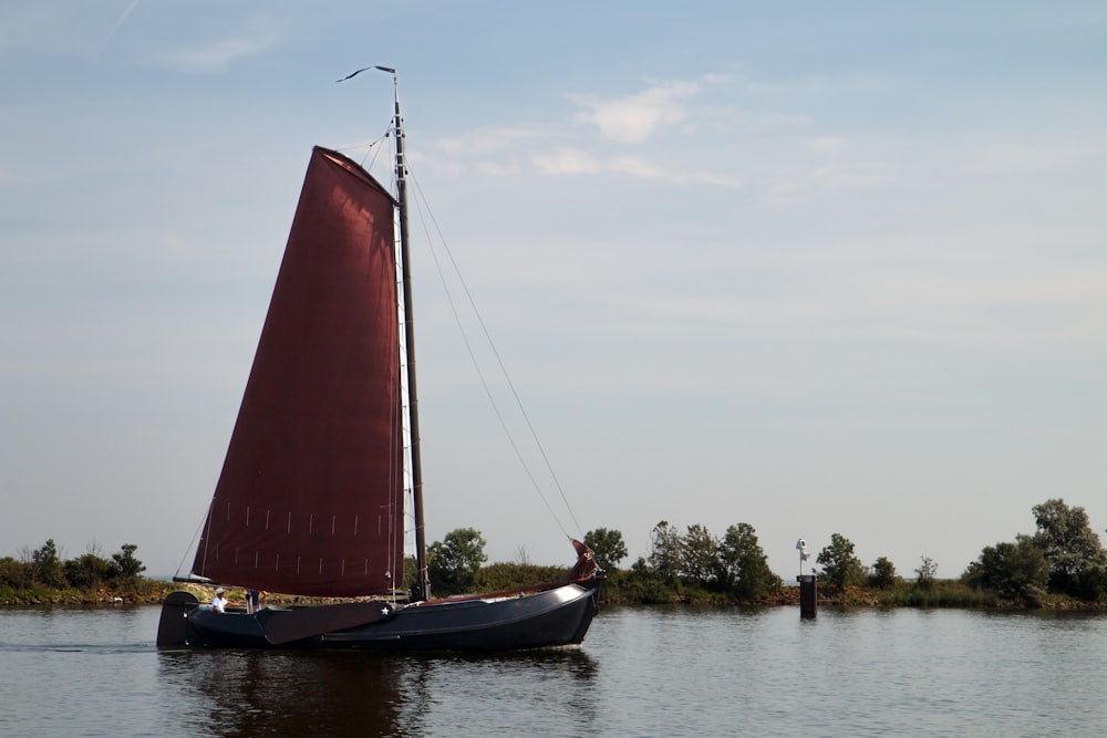 a sailboat with a red sail is in the water
