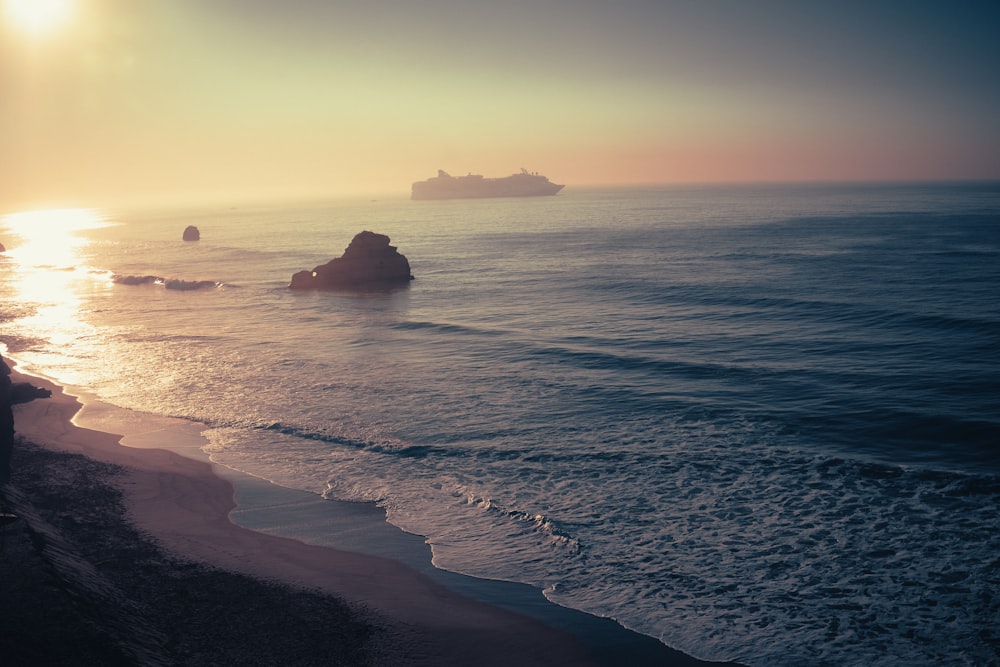 a couple of people standing on top of a beach near the ocean