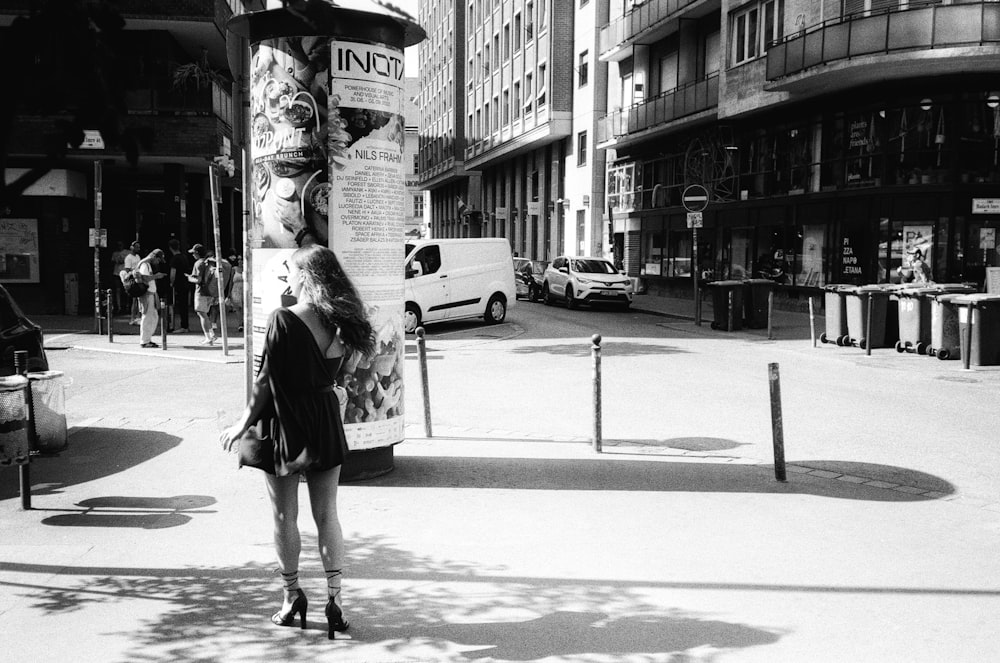 a black and white photo of a woman standing in the middle of a street