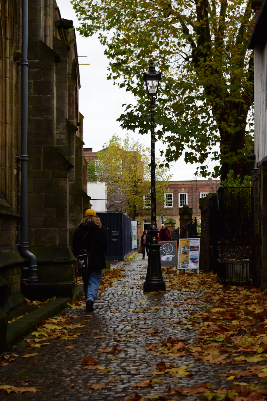 Person walking along a cobbled street lined with autumn leaves in Leicester, ideal for a relaxed first meeting after chatting on free dating sites in Leicester