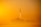 A rocket is launching into the sky, leaving a trail of exhaust against a vibrant yellow-orange backdrop. The image captures the moment of ascent with smoke visible near the ground.