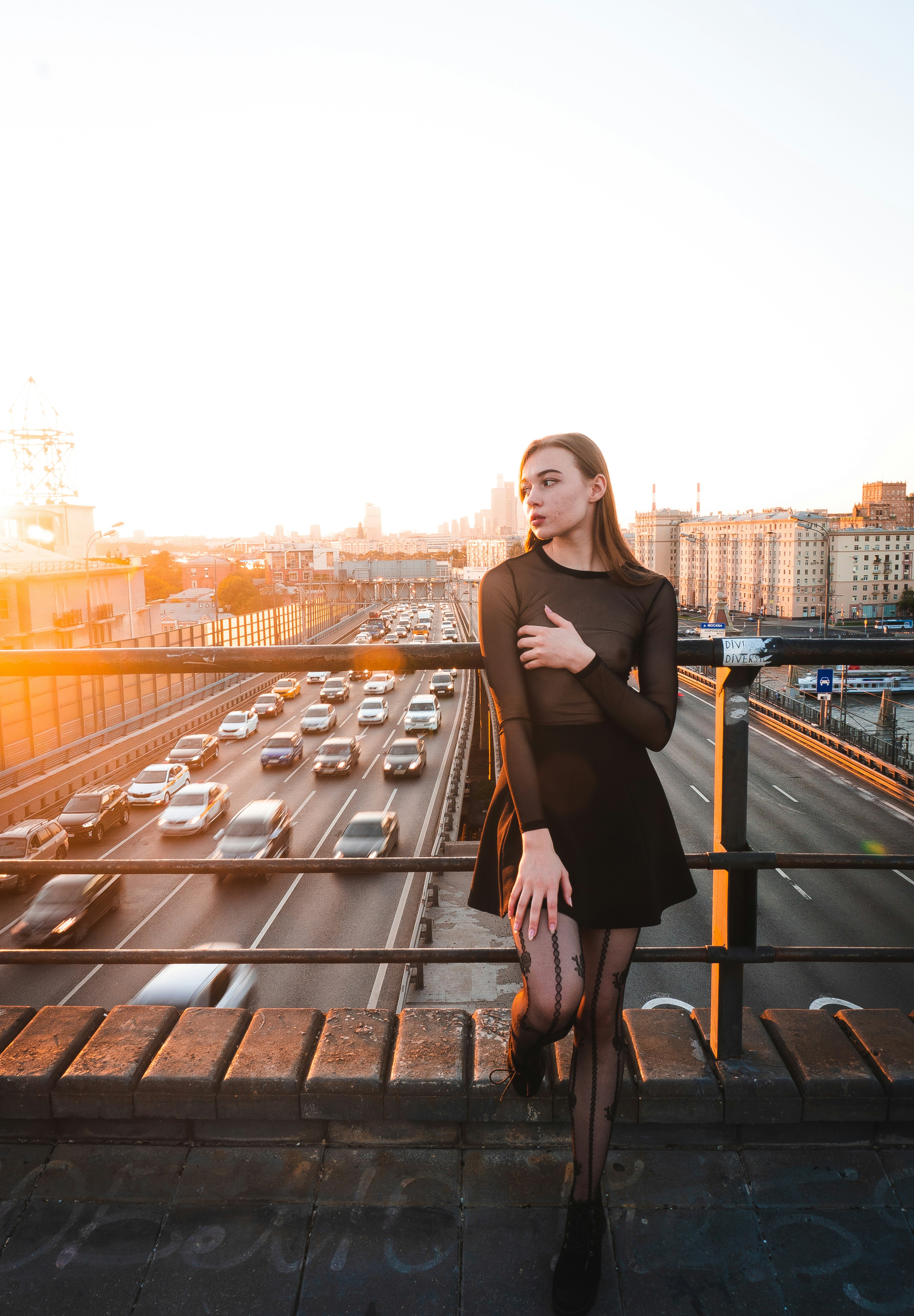 una mujer con un vestido negro de pie en un puente