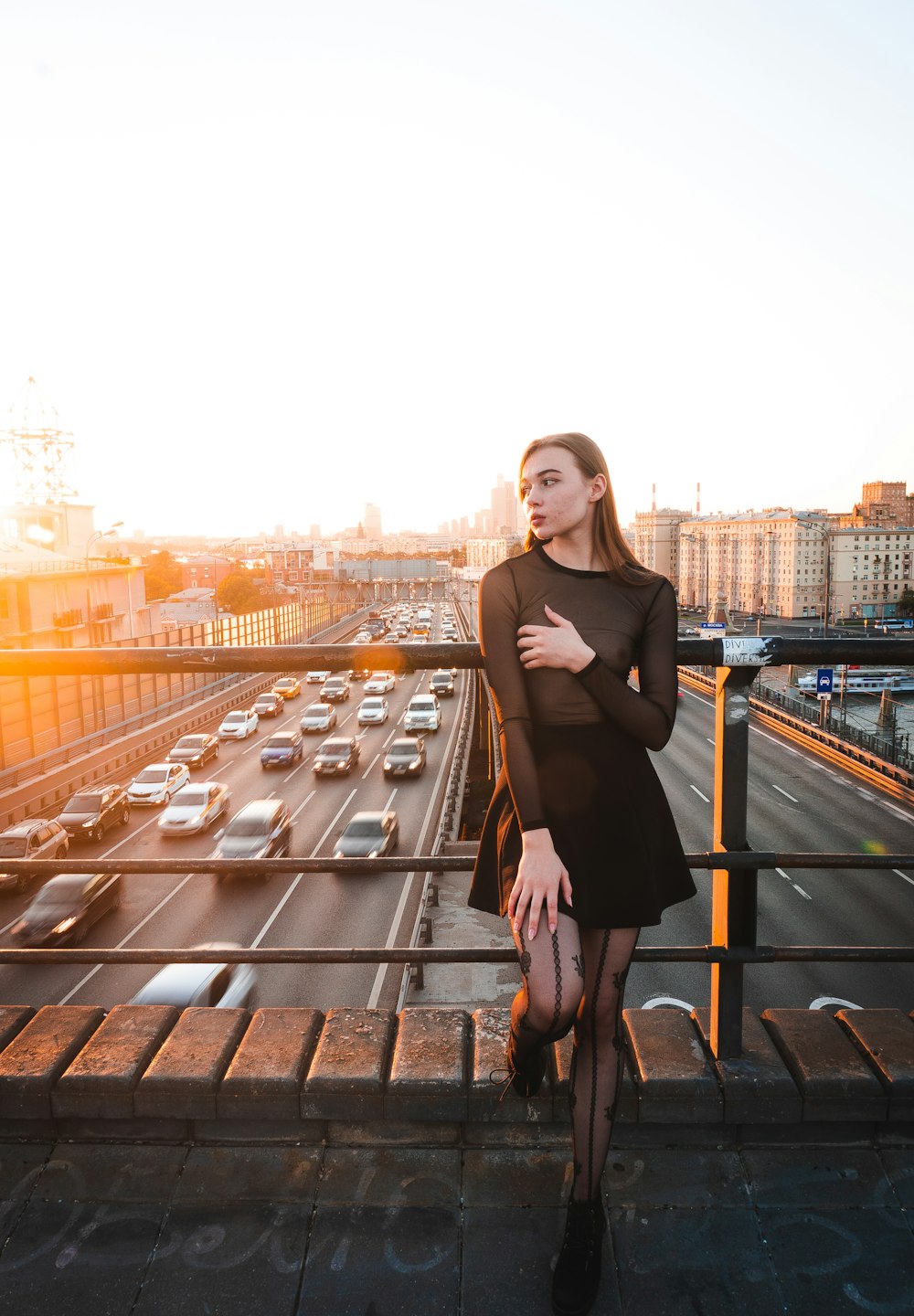 a woman in a black dress standing on a bridge