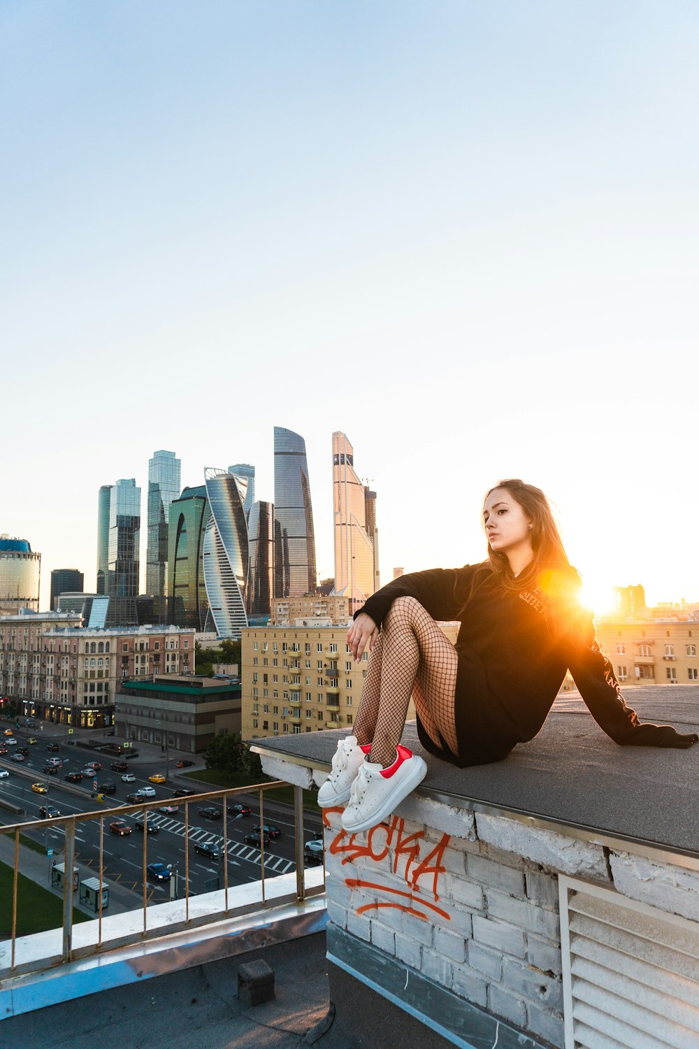 a woman sitting on a ledge with a city skyline in the background