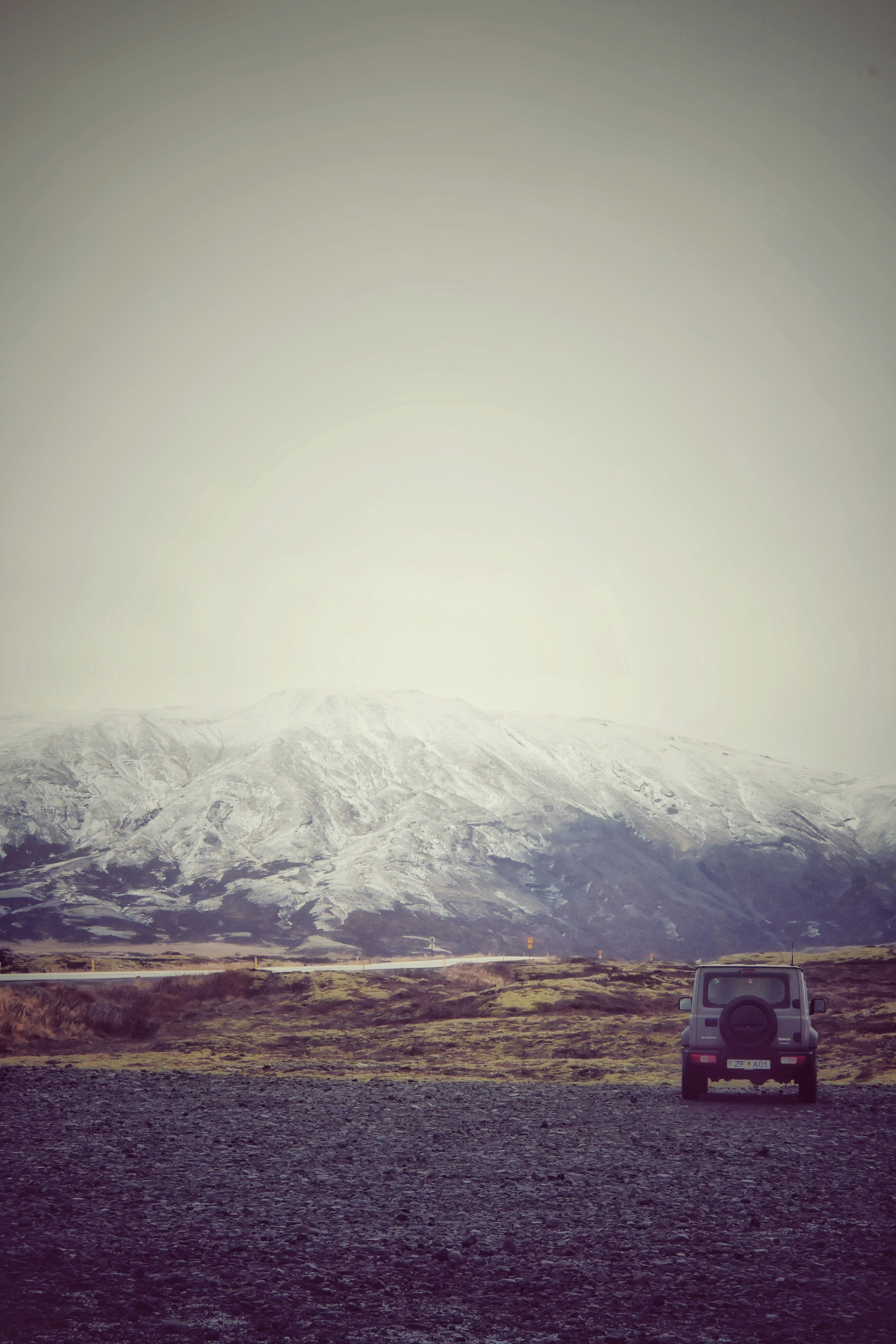 a car parked on the side of a road in front of a mountain