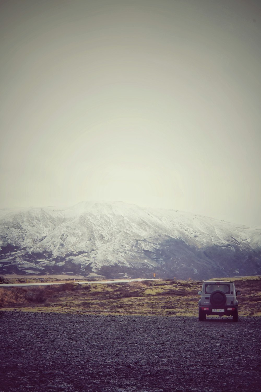 a car parked on the side of a road in front of a mountain