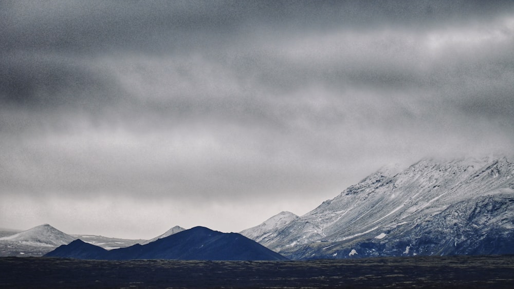 a snow covered mountain range under a cloudy sky