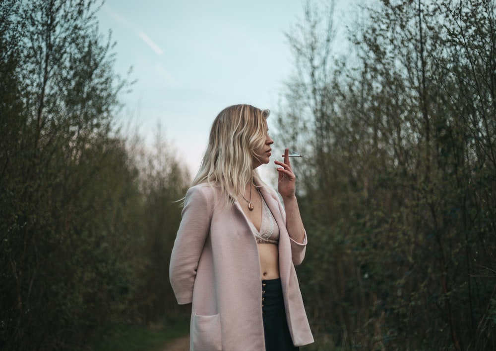 a woman in a pink coat smoking a cigarette