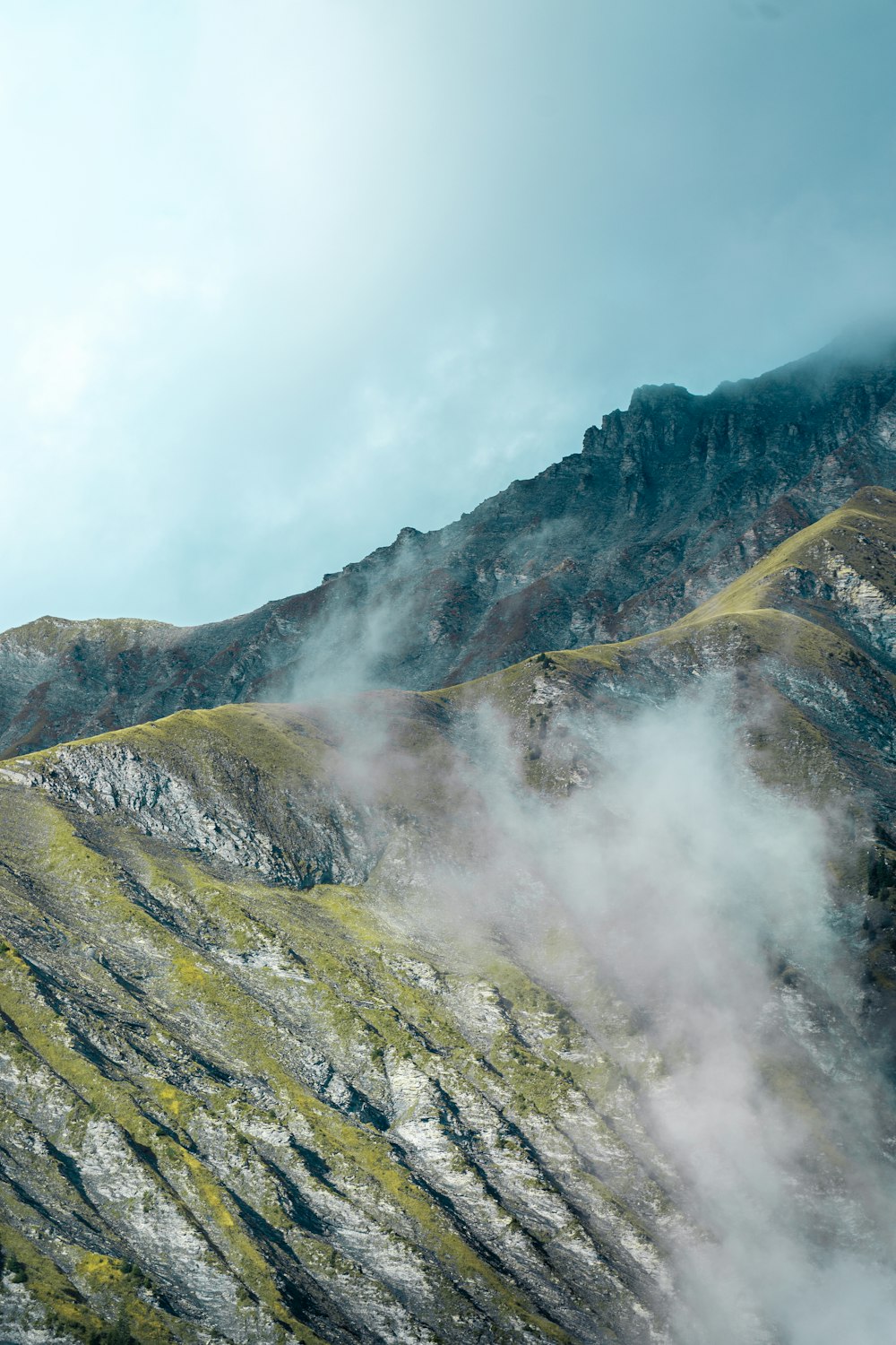 Una vista de una montaña con muchas nubes saliendo de ella