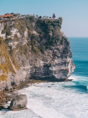Scenic view of Uluwatu temple perched on a cliff at sunset with ocean background