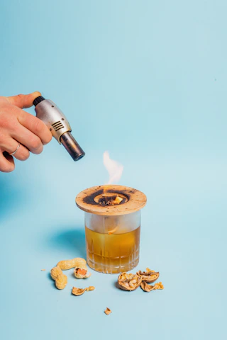 Close-up of artisan hands carefully tending to glowing embers in a traditional mezcal distillation process.