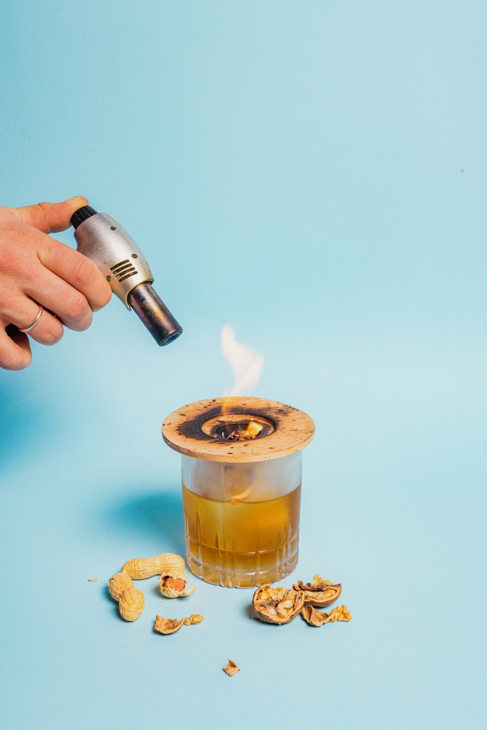 a person holding a lighter over a cup filled with liquid