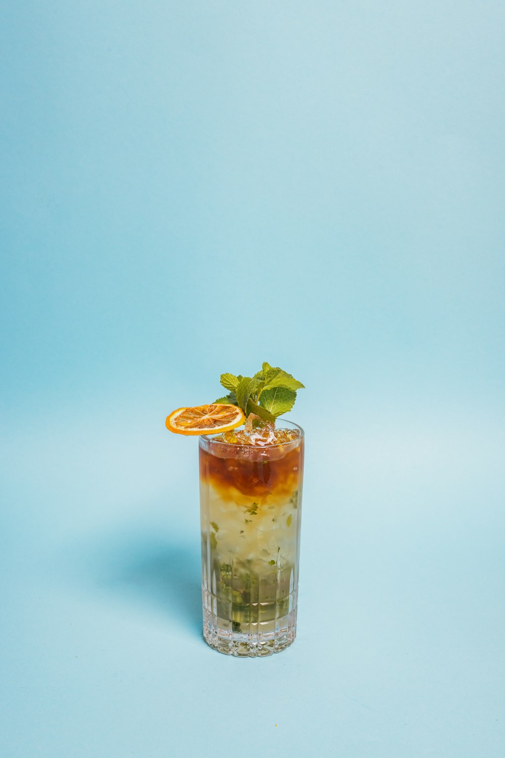 a glass with a drink and an orange slice on a blue background