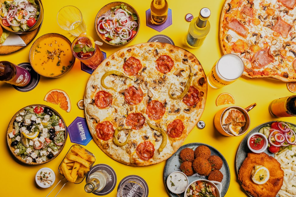 uma mesa amarela coberta com pizza e outros alimentos