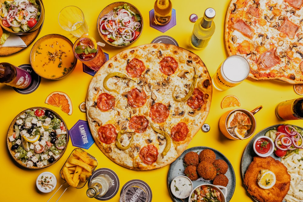 a yellow table topped with pizza and other food