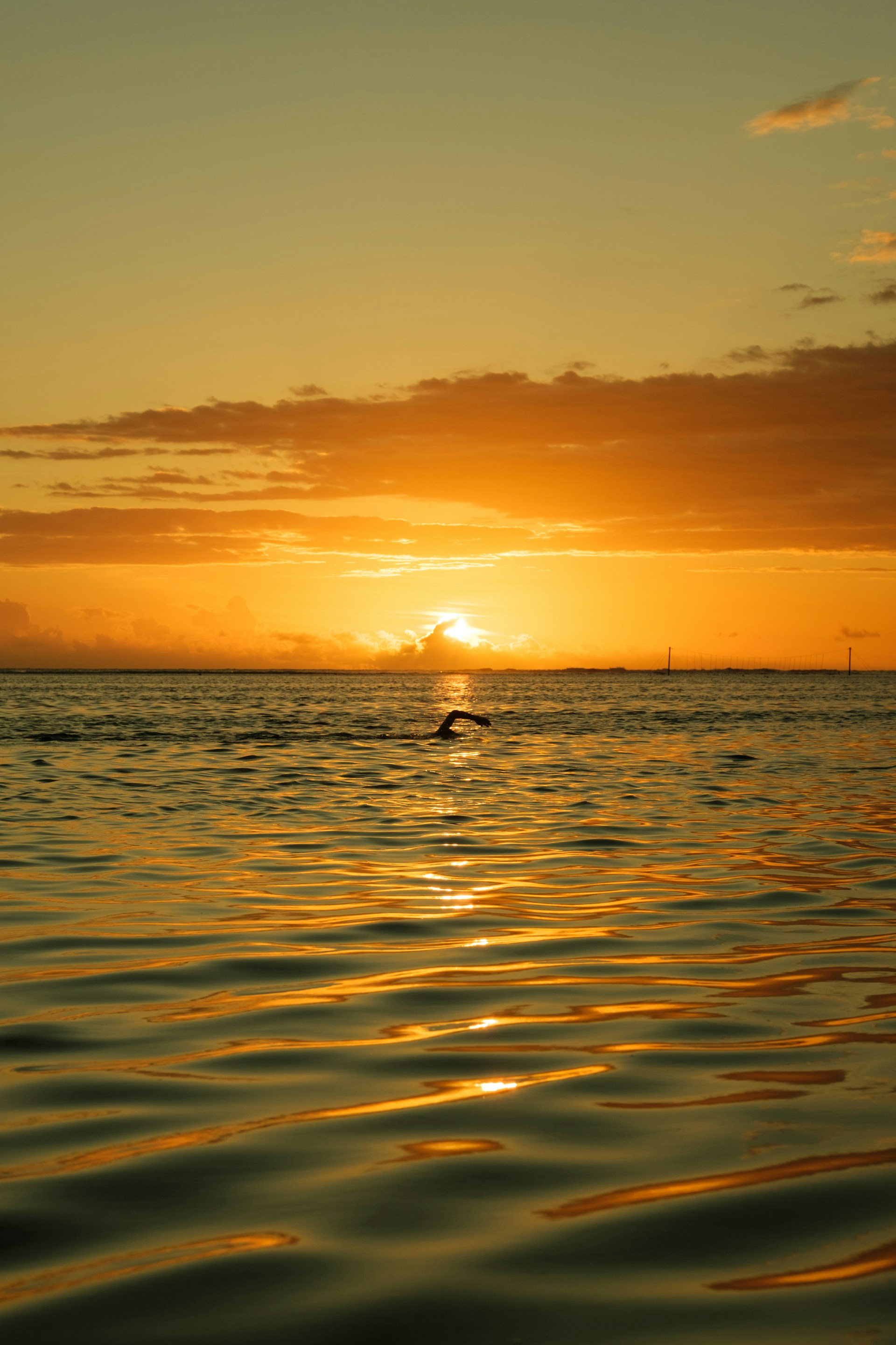 the sun is setting over the ocean with a boat in the distance