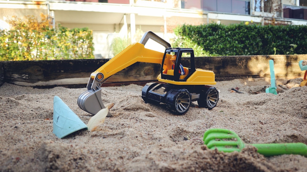 砂を掘る黄色いおもちゃのブルドーザー
