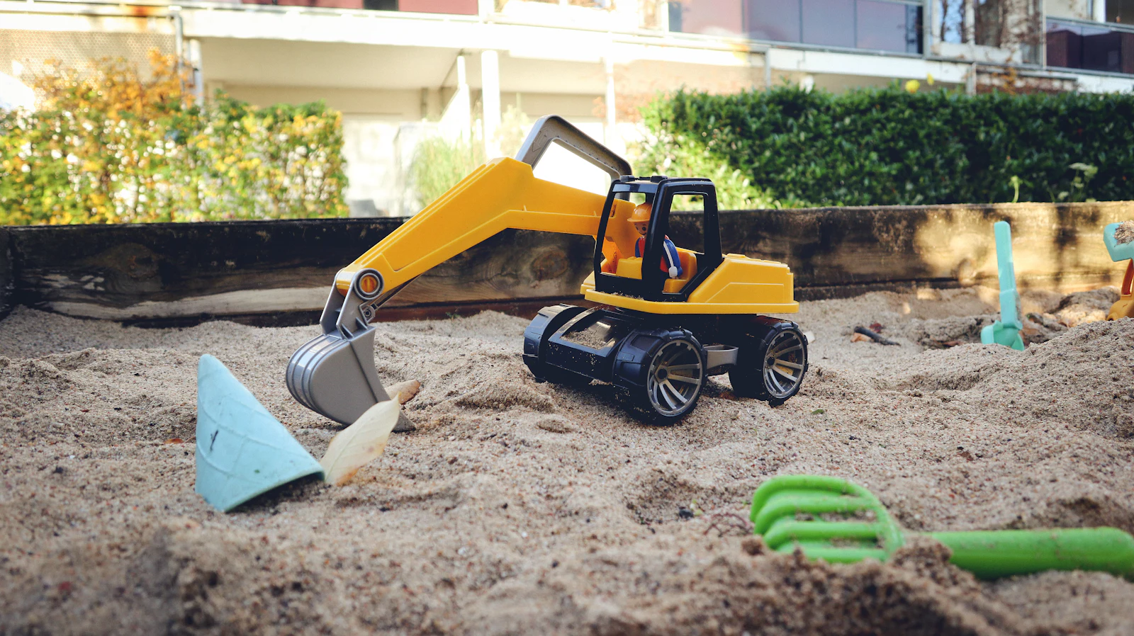 Excavadora amarilla a escala trabajando sobre la arena del arenero de RC Arena
