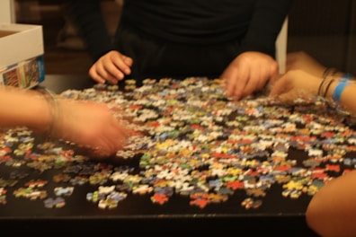 Brightly colored puzzles spread out on a table with a child’s hands assembling pieces.
