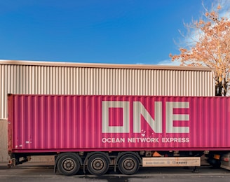 a pink semi truck parked in front of a building