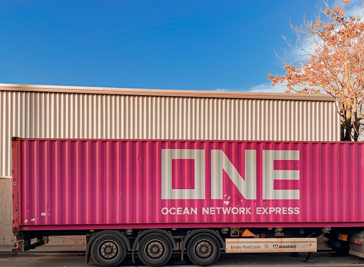 a pink semi truck parked in front of a building