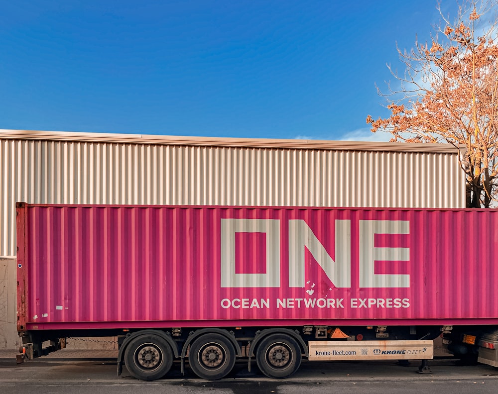 a pink semi truck parked in front of a building