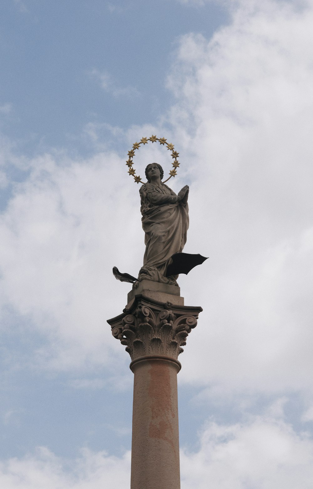 a statue on top of a pillar with a wreath around it