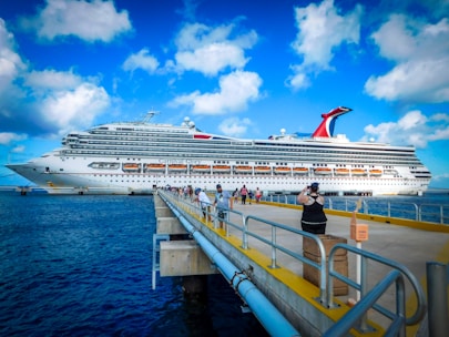 A joyful family boarding a Carnival cruise ship under bright blue skies.