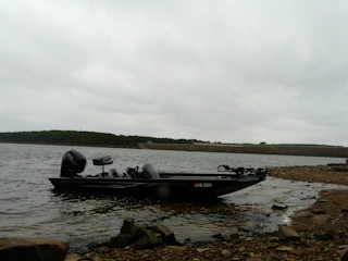 Angler putting on a life vest beside a fishing boat under moody skies.