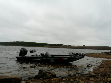Angler putting on a life vest beside a fishing boat under moody skies.
