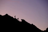 Sunset silhouette of climbers atop a ridge after a multi-day expedition prep.