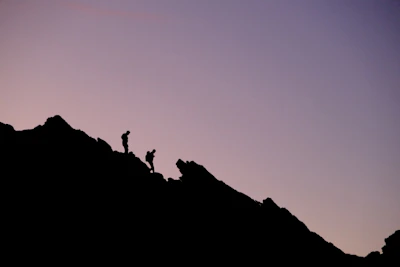 Sunset silhouette of climbers atop a ridge after a multi-day expedition prep.