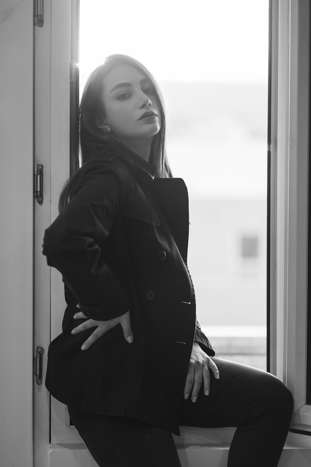 a woman sitting on a window sill looking out the window