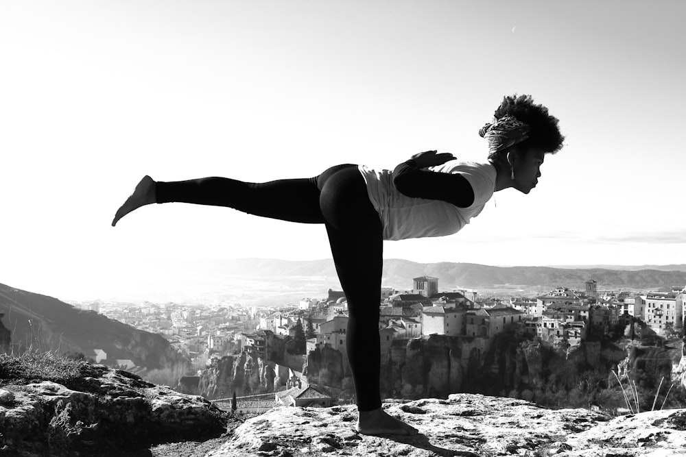 a woman doing a yoga pose on top of a mountain