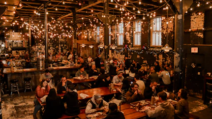 A warm, inviting photo of the founder engaging with staff in a bustling pub environment.